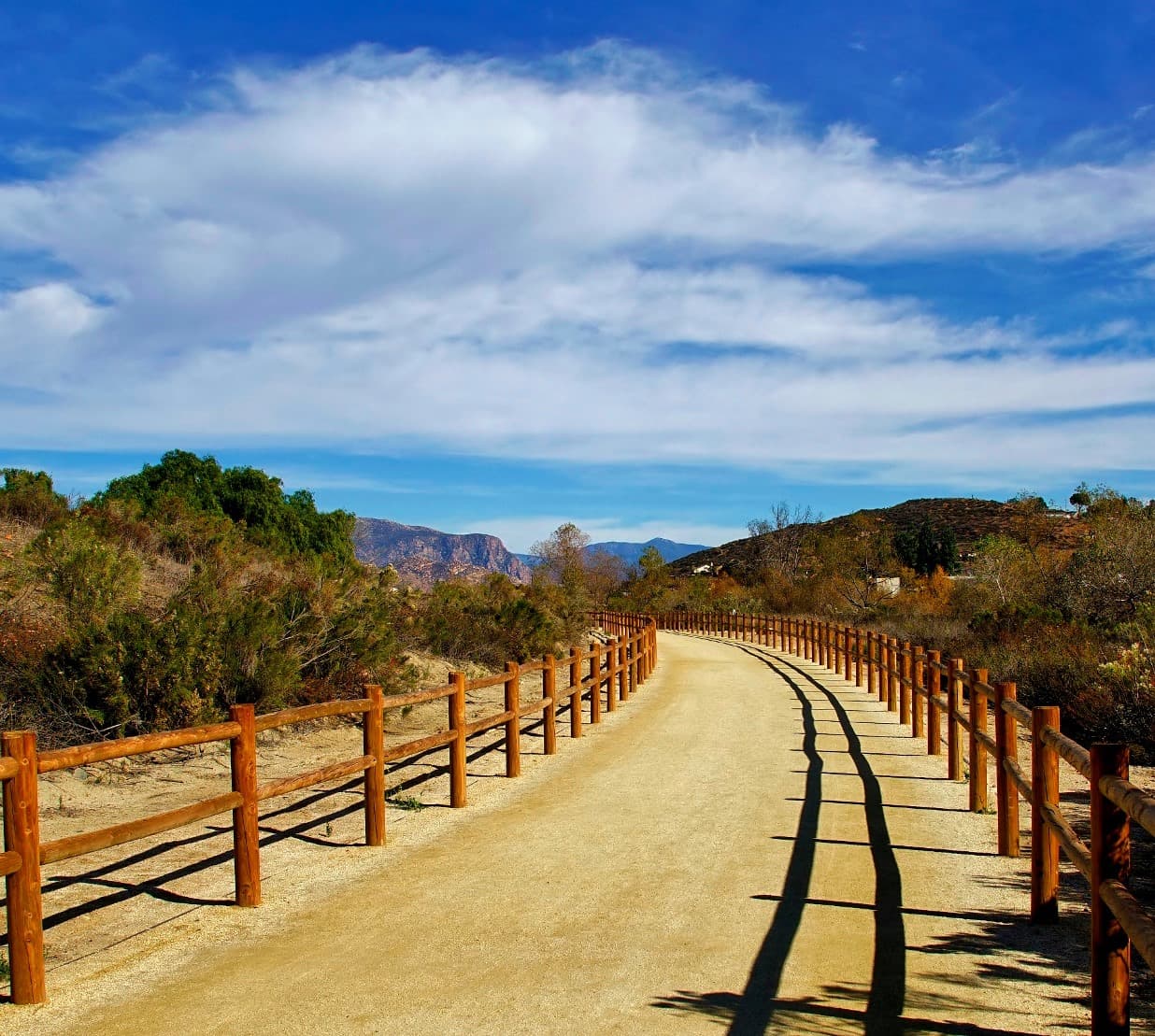 Walker Preserve Trail along the San Diego River in Santee with rustic wood fencing and distant mountains