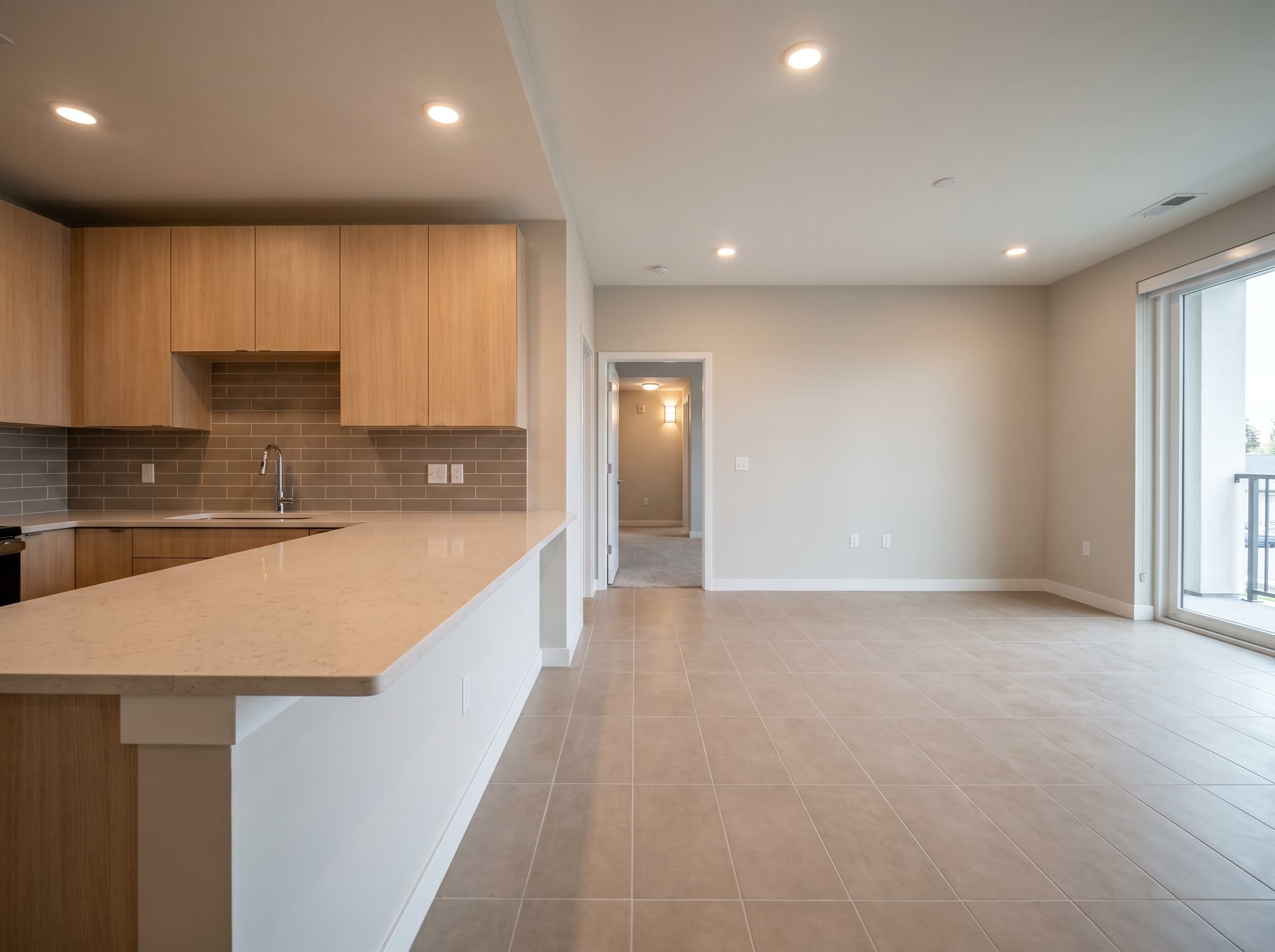 Multifamily apartment interior with consistent tile flooring, backsplash, and countertop finish